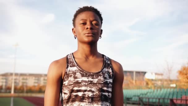 Portré egy aranyos fiatal fekete lány egy ujjatlan mez áll a sugár nap a focipályán során edzés. Lassú mozgás. — Stock videók