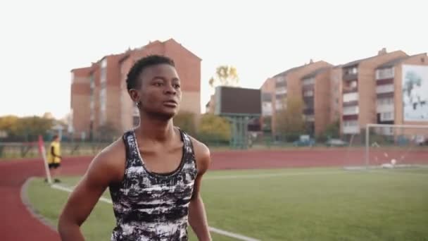 Ein schweres schwarzes Mädchen läuft während des Trainings für die Fußballmannschaft auf dem Laufband des Stadtstadions. Zeitlupe — Stockvideo