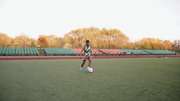 Молодая черная девушка тренируется на футбольном поле и практикует владение мячом в движении. Медленное движение — стоковое видео