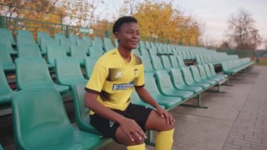 Belarus, Minsk - 20 Haziran 2021: Stadyumdaki memnun siyah bir kız seyirci koltuğundan kalkar ve maçtan önce futbol formasını düzeltir. Yavaş çekim