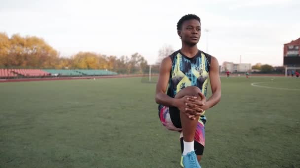 Junge Afroamerikanerin trainiert auf Fußballplatz und macht statische Dehnübungen im Stehen — Stockvideo