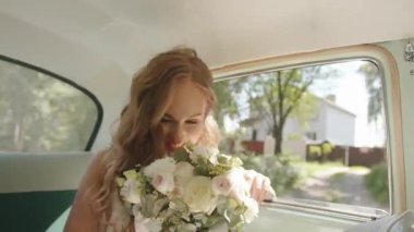 Dokunaklı genç bir gelinin portresi. Bir arabanın arka koltuğunda. Yaz günü elinde bir düğün buketiyle.