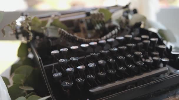 Close-up van een zwarte vintage typemachine omringd door eucalyptus twijgen. Auteurschap en creativiteit — Stockvideo