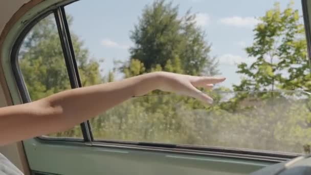 Închiderea mâinii mireselor ieșind pe fereastra unei mașini retro care circulă prin mediul rural. Vedere interioară. Slow motion — Videoclip de stoc