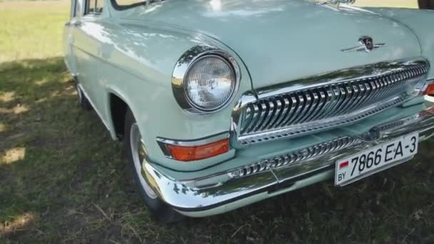 Bielorrússia. Região de Gomel. 21 Agosto 2021: Branco retro Volga Gaz 21 frente com logotipos de veados e close-up radiador cromado — Vídeo de Stock