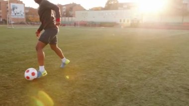 Afrika kökenli Amerikalı bir kadın futbol sahasında antrenman yapıyor ve top hareket halindeyken fetiş yapıyor. Yavaş çekim