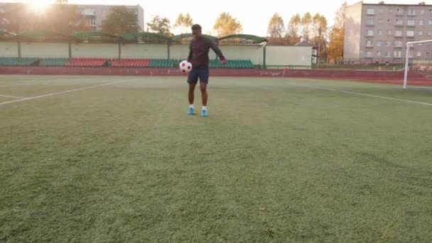 Una joven negra entrenando en el estadio de la ciudad y hace malabares con una pelota de fútbol y pisa el pie. Movimiento lento — Vídeos de Stock