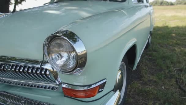 Close-up of the front of the rare white Volga Gaz 21 with a badge and a deer figurine on the hood of the car — Stock Video