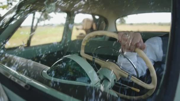 Primer plano de la mano de un hombre casado con una camisa blanca y chaleco que conduce un coche de época a través del parabrisas — Vídeos de Stock