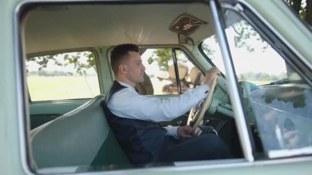 Aantrekkelijke jongeman zit achter het stuur van een retro Volga Gaz 21. Succesconcept — Stockvideo