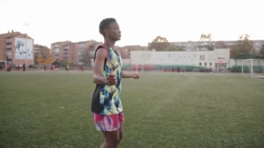 Şehir stadyumunda egzersiz yapan ve sırayla ip atlayan genç kız bacaklarını kaldırıyor.