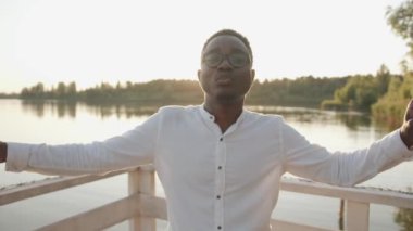 Genç siyah bir adam kollarını nehir kıyısının kenarlarına açıyor rahatlıyor ve sessizlik ve özgürlüğün tadını çıkarıyor. Yavaş çekim