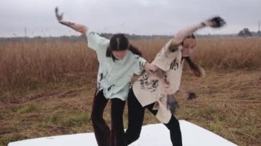 Siyah boyalı ellerle buğday tarlasında dans eden ve gösteri yaparken kıyafetlerini lekeleyen genç kızlar. Tehlike ve endişe kavramı