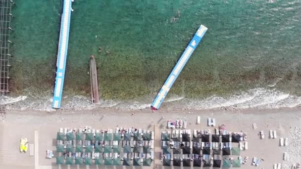 Vista superior de pontões modulares de plástico em mar azul claro e turistas descansando em uma praia branca. Zoom em vigor — Vídeo de Stock