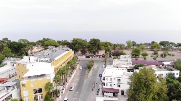 Drone tir de la rue centrale de la station balnéaire avec des voitures stationnées et un panorama de la mer fusionnant avec le ciel dans une brume blanche — Video