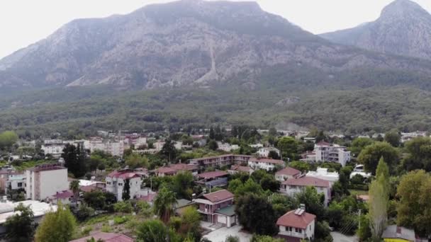 Vue aérienne d'une ville de montagne avec de beaux chalets entourés de palmiers et un parking d'autobus sur la rue principale — Video