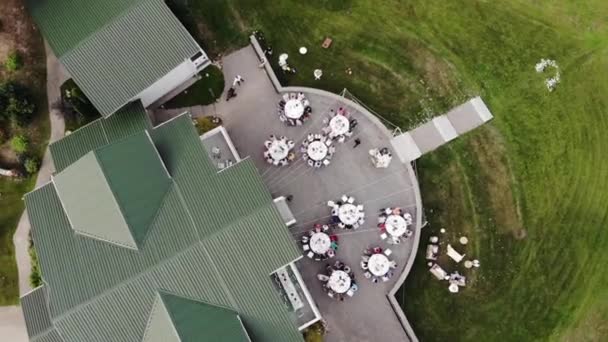 Horní pohled na terasu krásného panského domu s hosty a ženicha s nevěstou u prostřených stolů na svatební oslavě po obřadu — Stock video