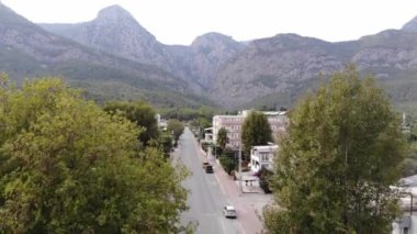Palmiye ağaçları ve ana caddede bir otobüs parkıyla çevrili güzel kulübeleri olan bir dağ kasabasının hava manzarası.
