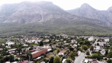 Kasabanın ağaçlarla kaplı dağların eteklerindeki hava manzarası ve otoparkta bir otobüs kümesi olan merkez yol.