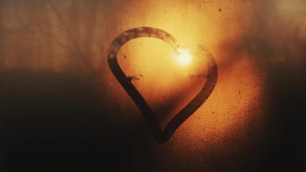 Drawing of a heart on a foggy window against the backdrop of a sunset or dawn. Love and relationship concept. Copy spase — Stock Video