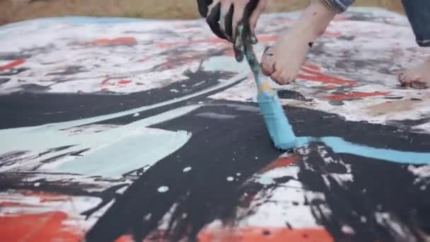 Een getalenteerd jong meisje gaat blootsvoets op een doek in een tarweveld en schildert een abstract beeld met een borstel. Creativiteitsconcept — Stockvideo