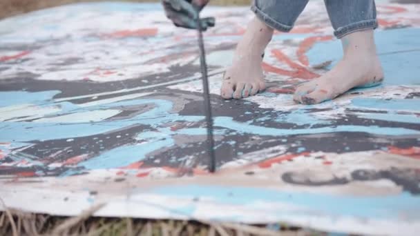 Talentovaný mladý umělec s bosýma nohama potřísněnýma barvou kreslí kreativní abstraktní obrázek se štětcem na plátně v pšeničném poli — Stock video