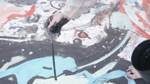 Egy kreatív művész rajzol egy absztrakt képet egy nagy vászonra, és fekete festékkel körvonalazza a foltokat és fröccsenéseket. Művészet és tehetség fogalma — Stock videók