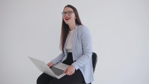 Başarılı genç bir iş kadını dizüstü bilgisayarıyla kucağında oturur ve bulaşıcı bir şekilde güler. Güçlü ve bağımsız kadın konsepti — Stok video
