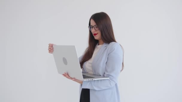 Successful young business woman leader and professional working on a laptop holding it in her hands on an isolated white background — стоковое видео