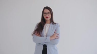 Olağanüstü genç iş kadını kollarını göğsüne kavuşturmuş kaşlarını çatmış, kaşlarını çatmış ve şaşırmış bir şekilde ayakta duruyor.