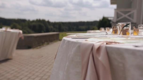 天然の結婚式のパーティーでゲストのためのガラス製品と蜂蜜瓶付きのテラスのテーブル。カメラはフォーカスを変更します — ストック動画