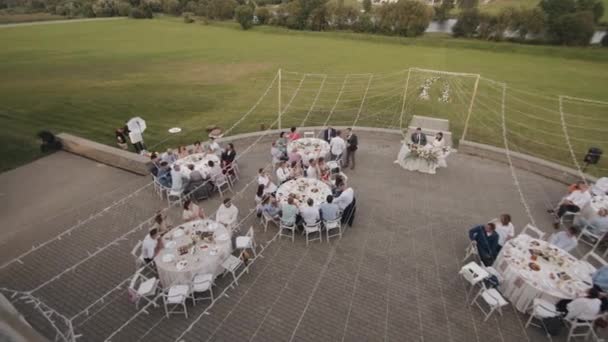ベラルーシ。Minsk2021年8月21日:結婚式に敬意を表し、お祝いのディナーの間にテーブルに座って新婚旅行やゲストとテラスの空中ビュー — ストック動画