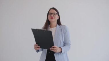 Siyah gözlüklü güzel genç iş kadını elinde belgelerle gezip gülüyor.