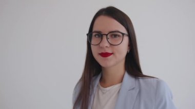 Beyaz arka planda gözlüklü kendine güvenen bir iş kadınının portresi. Liderlik ve başarı kavramı. Yavaş çekim