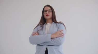 Kendine güvenen genç iş kadını kollarını göğsünde kavuşturmuş ve gururla gülümsüyor ve bir şeyler söylüyor. Kadın gücü