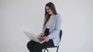 Başarılı genç bir iş kadını dizüstü bilgisayarıyla kucağında oturur ve bulaşıcı bir şekilde güler. Güçlü ve bağımsız kadın konsepti