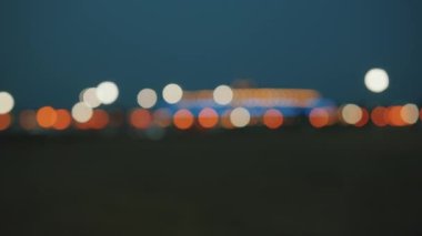Sokak lambalarının bulanık ışıkları ve gece gökyüzünün arka planında büyük parlak bir nesne. Bokeh etkisi