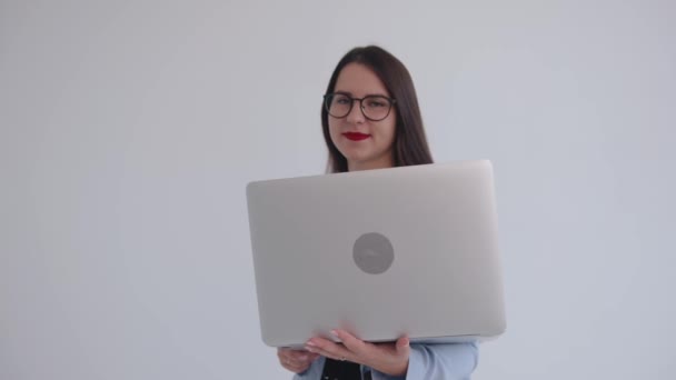 Mulher de negócios jovem confiante em óculos pretos sorrindo olha para fora por trás de uma tela de laptop e olha para cima sonhadoramente — Vídeo de Stock