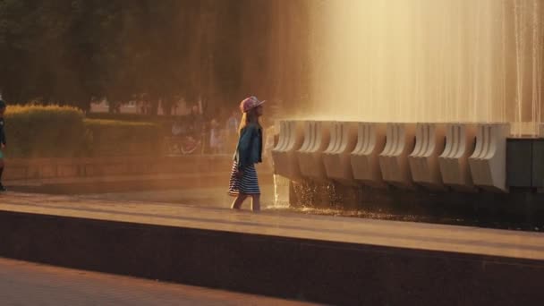 Minsk, Bielorrusia - 29 de junio de 2021: Vacaciones familiares en el parque de la ciudad en una noche de verano. Los niños corren alrededor de la fuente y persiguen palomas. Movimiento lento — Vídeo de stock