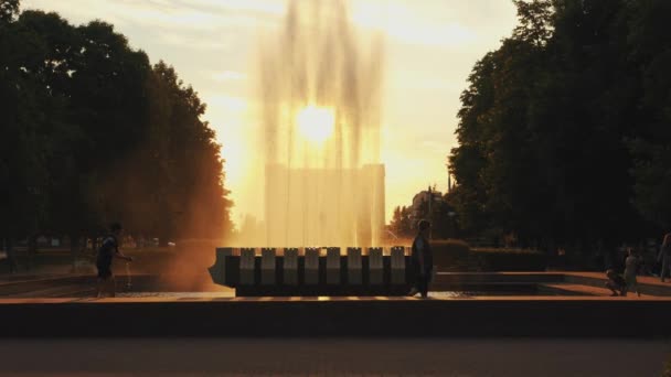 Minsk, Weißrussland - 29. Juni 2021: Spritzer Brunnen bei Sonnenuntergang auf dem Stadtplatz mit Tauben und Kindern, die auf der Brüstung am Wasser spielen. Zeitlupe — Stockvideo