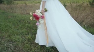 Tarlanın karşısındaki damat, elinde bir buket yıldız çiçeği, elinde bir tren ve şık bir elbiseyle gelinin elini tutar.