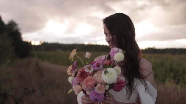 세련 된 옷을 입은 매력적 인 신부 가손에 다 일리아 꽃다발을 들고 그 위에 리본 을 곧게 펴 준다. 느린 동작 — 비디오