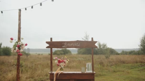 Contatore di legno con un puntatore per limonata a una festa di nozze in natura decorato mazzi di fiori e una lanterna — Video Stock
