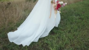 Gelinin elinde bir buket yıldız çiçeği ve trenle şık bir elbiseyle damadın yanında yeşil çimlere basar.