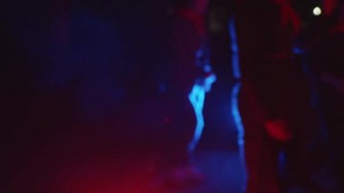 Minsk, Belarus, 9 Ocak 2022: Bulanık insan figürleri, bir hangardaki spot ışığından mavi ışığa doğru ilerler.