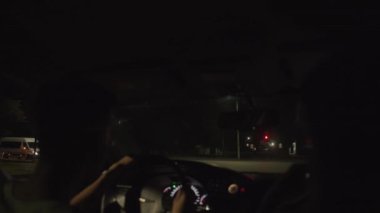 Minsk, Belarus, 9 Ocak 2022: Araba kullanan gözlüklü genç bir adam ve arabanın ön camından yaz gecesi şehri manzarası.