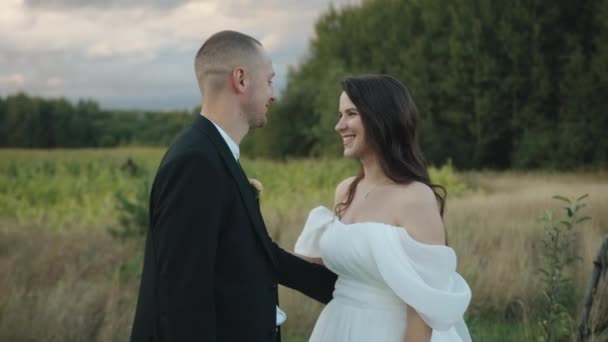 Happy laughing newlyweds stand embracing and look into each other eyes while standing in nature. Gerakan lambat — Stok Video