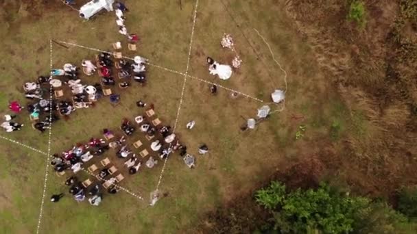 Top view of the bride and groom at the flower arch and rows of chairs with guests on the lawn at the marriage rite — Stock Video