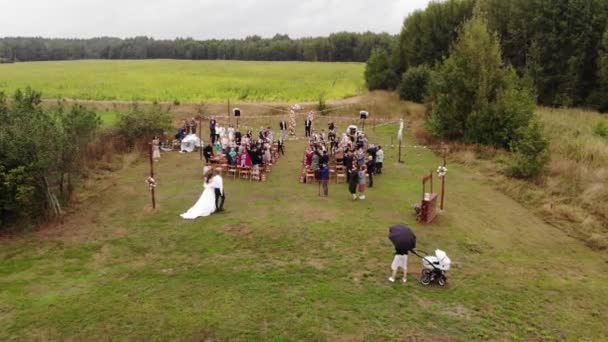 Minsk, Vitryssland - 29 juni 2021: Flygfoto av bruden med sin far gående till brudgummen vid blomsterbågen på gången mellan gäster i naturen — Stockvideo