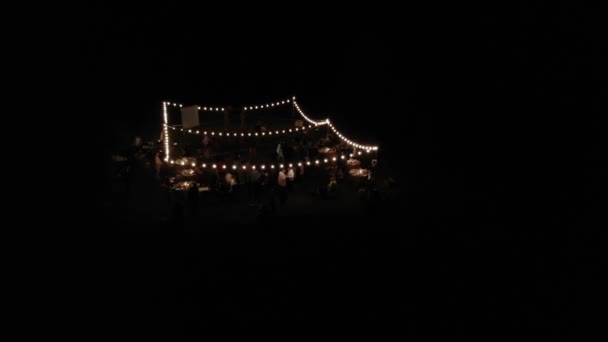 Aerial view of an open area decorated with burning garlands at a wedding party in the evening — Stock Video